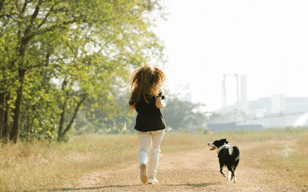 woman running with her black and white dog in a park